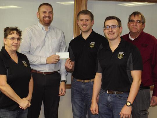 Missy Hoppe (left), Jared Bessmer, Garret Kuhl and James Bessmer receive check from Aaron Gutz (second from left), a member of Community HOME Team