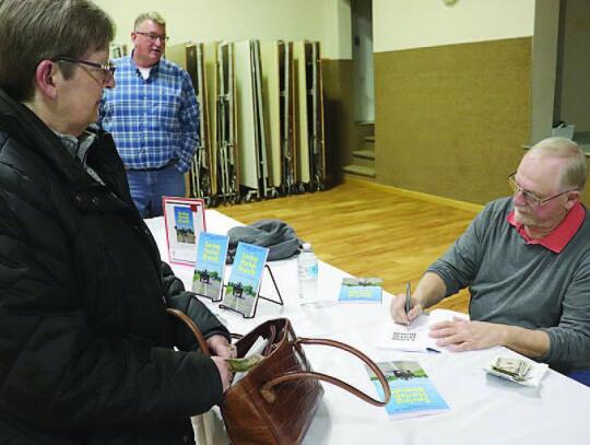 At left, Lea McKenna waits as Harlan Brandt signs the book, “Saving Harlan Brandt,” for her. At right, Kent Warneke talks about the making of the book.